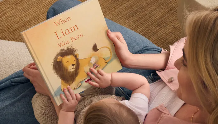 a mother and baby ready a wonderbly book with a lion on the front cover