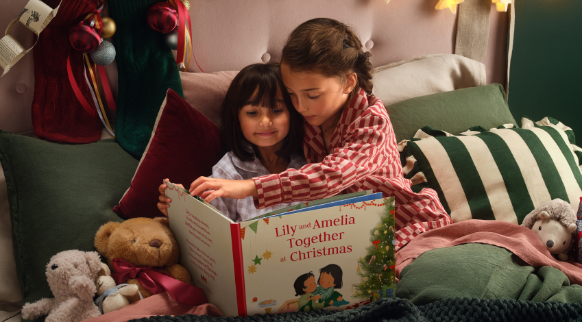 two girls at christmas reading a wonderbly book